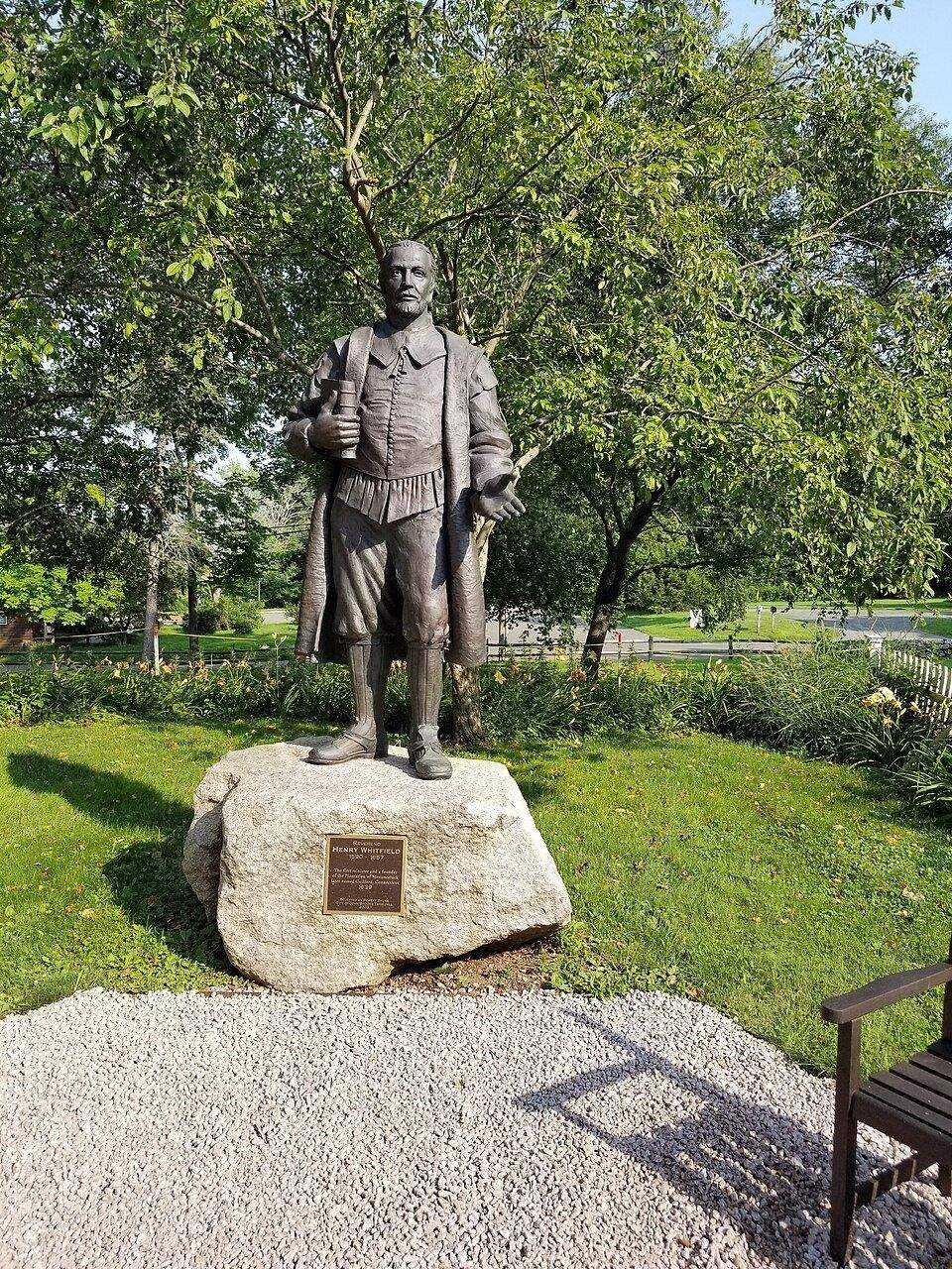 Bronze statue in a park setting in Guilford, CT with trees and benches