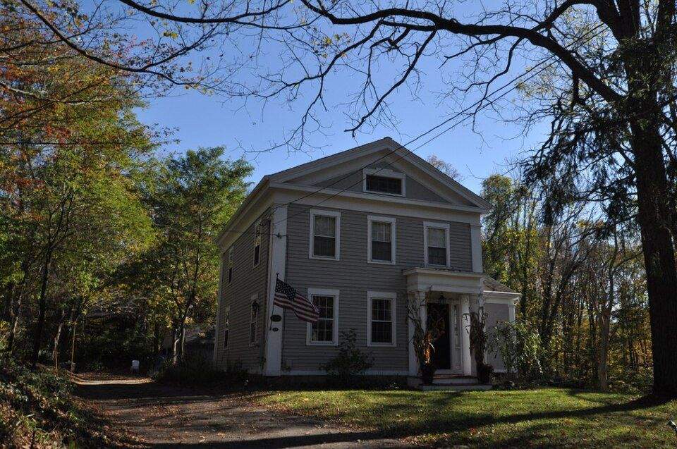 Historic colonial home with American flag on a tree-lined street in Woodbridge, CT